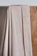 Tissu velours côtelé beige rosé, drapé sur un plan de travail en bois.
