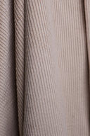 Gros plan sur les grosses côtes du velours Bubble rose pâle, drapé sur un support en bois, texture douce et duveteuse.
