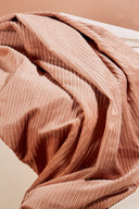 Tissu velours côtelé rose saumon froissé en plis souples, gros plan sur la texture côtelée.