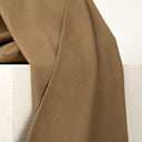 Tissu uni camel drapé sur un socle blanc, vue rapprochée du tombé