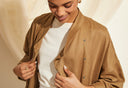 Femme souriante portant une veste longue camel sur un t-shirt blanc, vestiaire Atelier Brunette