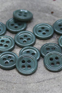 Close-up of the same small four-hole round buttons, highlighting the shine of the material.