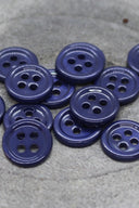 Close-up of the same small four-hole round buttons, highlighting the shine of the material.