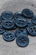 Close-up of the same small four-hole round buttons, highlighting the shine of the material.