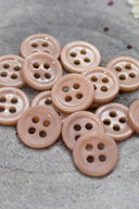 Close-up of the same small four-hole round buttons, highlighting the shine of the material.
