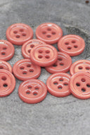 Close-up of the same small four-hole round buttons, highlighting the shine of the material.