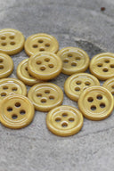 Close-up of the same small four-hole round buttons, highlighting the shine of the material.