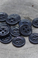 Close-up of the same small round four-hole buttons, highlighting the shine of the material.