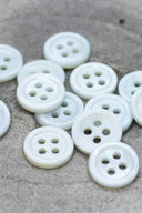 Close-up of the same small four-hole round buttons, highlighting the shine of the material.