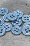 Close-up of the same small four-hole round buttons, highlighting the shine of the material.