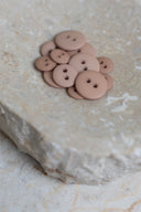 Les boutons vus de dessus, empilés au centre d'une pierre beige marbrée.