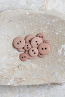 Les boutons vus de dessus, empilés au centre d'une pierre beige marbrée.