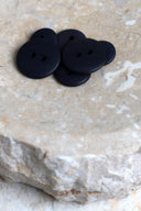 Les boutons vus de dessus, empilés au centre d'une pierre beige marbrée.