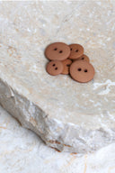 Les boutons vus de dessus, empilés au centre d'une pierre beige marbrée.