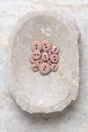 Top-down view of the buttons, stacked at the centre of a marbled beige stone.