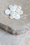 Top-down view of the buttons, stacked at the centre of a marbled beige stone.
