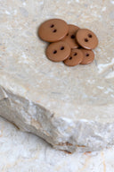 Top-down view of the buttons, stacked at the centre of a marbled beige stone.