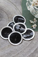 Close-up of the same enameled buttons rimmed with pearl, revealing the glossy texture and white trim.