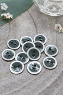 Close-up of the same enameled buttons rimmed with pearl, revealing the glossy texture and white trim.