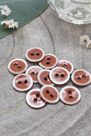 Close-up of the same enameled buttons rimmed with pearl, revealing the glossy texture and white trim.
