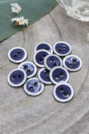 Close-up of the same enameled buttons rimmed with pearl, revealing the glossy texture and white trim.