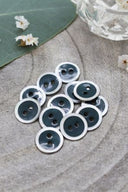 Close-up of the same enameled buttons rimmed with pearl, revealing the glossy texture and white trim.