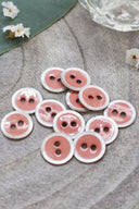 Close-up of the same enameled buttons rimmed with pearl, revealing the glossy texture and white trim.
