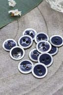 Close-up of the same enameled buttons rimmed with pearl, revealing the glossy texture and white trim.