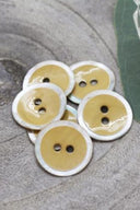 Close-up of the same enameled buttons rimmed with pearl, revealing the glossy texture and white trim.