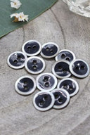 Close-up of the same enameled buttons rimmed with pearl, revealing the glossy texture and white trim.