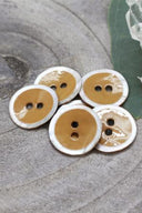 Close-up of the same enameled buttons rimmed with pearl, revealing the glossy texture and white trim.