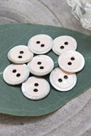Close-up of the same enameled buttons rimmed with pearl, revealing the glossy texture and white trim.