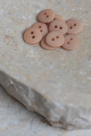 Les boutons vus de dessus, empilés au centre d'une pierre beige marbrée.