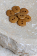 Les boutons vus de dessus, empilés au centre d'une pierre beige marbrée.