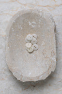 Top-down view of the buttons, stacked at the centre of a marbled beige stone.