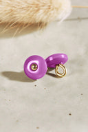 Domed round button with a central gold stud, glossy bubblegum pink-violet color, photographed from the front and in profile showing the gold metal shank, on a light background.
