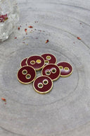 Close-up of the same round buttons rimmed with a gold trim, highlighting the shine of the enamel.