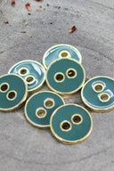 Cinq boutons ronds à deux trous, finition émaillée brillante vert cactus, cerclés d'un liseré métallique doré, posés sur une pierre grise avec des pétales de fleurs séchées éparpillés en arrière-plan.