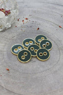 Close-up of the same round buttons rimmed with a gold trim, highlighting the shine of the enamel.