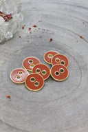Close-up of the same round buttons rimmed with a gold trim, highlighting the shine of the enamel.