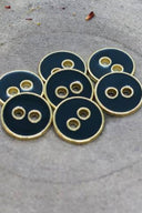 Close-up of the same round buttons rimmed with a gold edge, highlighting the shine of the enamel.