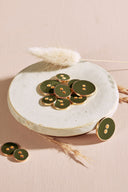Close-up of the same round buttons rimmed with a gold edge, highlighting the shine of the enamel.