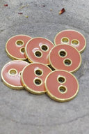 Close-up of the same round buttons rimmed with a gold trim, highlighting the shine of the enamel.