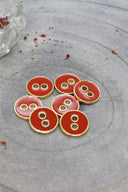 Close-up of the same round buttons rimmed with a gold edge, highlighting the shine of the enamel.