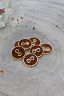 Close-up of the same round buttons rimmed with a gold edge, highlighting the shine of the enamel.