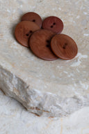 Les boutons vus de dessus, empilés au centre d'une pierre beige marbrée.