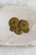 Autre vue rapprochée des boutons sur la pierre beige marbrée, sous un angle différent.