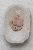Les boutons vus de dessus, empilés au centre d'une pierre beige marbrée.