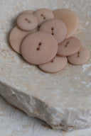 Autre vue rapprochée des boutons sur la pierre beige marbrée, sous un angle différent.