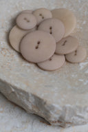 Vue rapprochée des mêmes boutons sur le bord d'une pierre beige marbrée.